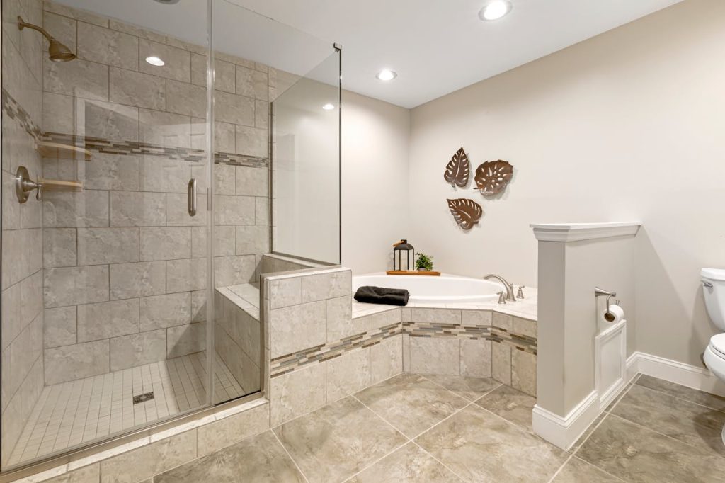 Spacious modern bathroom featuring a glass shower, tub, and stylish decor.